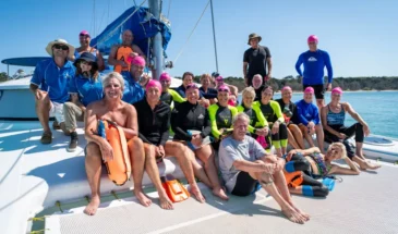 Group of swimmers smiling for the camera on a boat at Moreton Bay.
