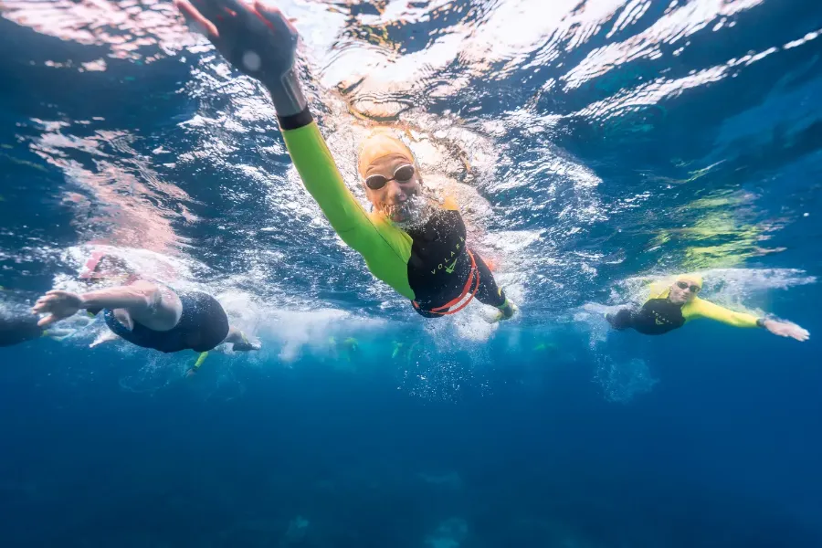 Photograph of three swimmers in the ocean